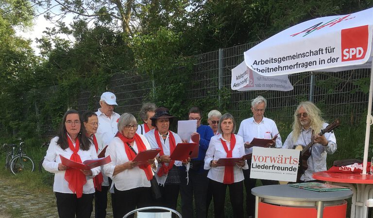 Chor: Männer und Frauen mit roten Schals