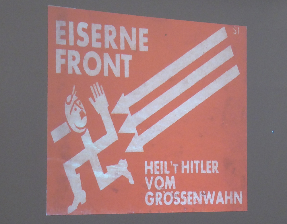 Banner mit Aufschrift "Eiserne Front" und drei Pfeilen, die dein Hakenkreuz bedrohen