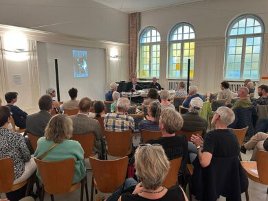 Publikum vor dem Podium mit zwei Männern