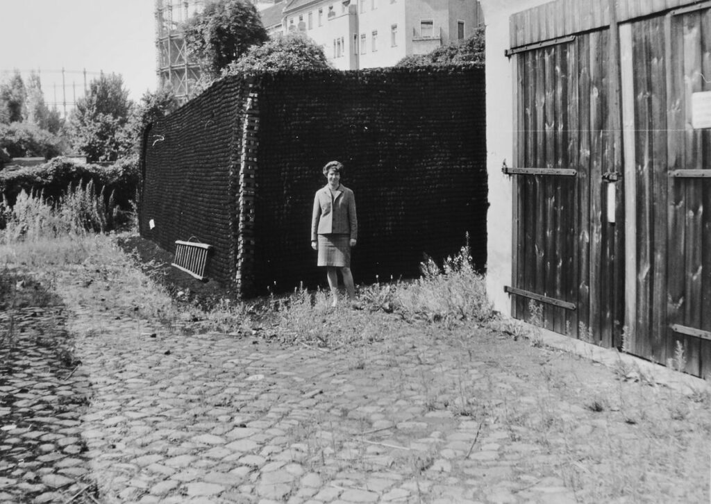 Frau vor gestapelter Kohle im Hintergrund Gasometer