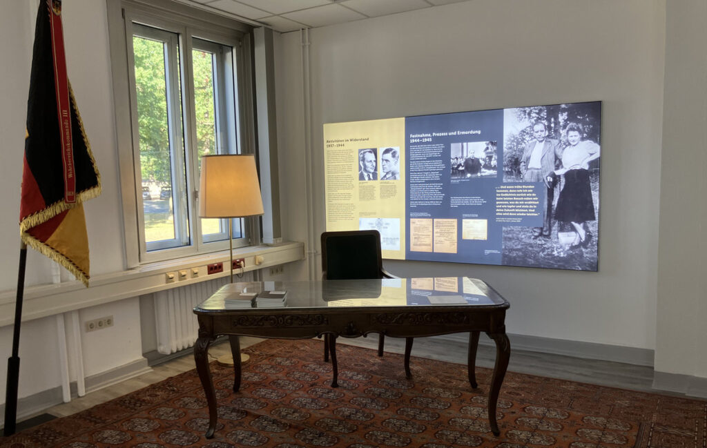 Deutschlandfahne, Schreibtisch und dahinter Ausstellungstafeln